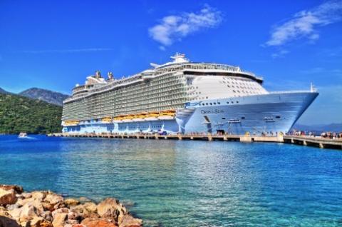 Docked Cruise Ship with blue sky and white clouds and blue ocean.